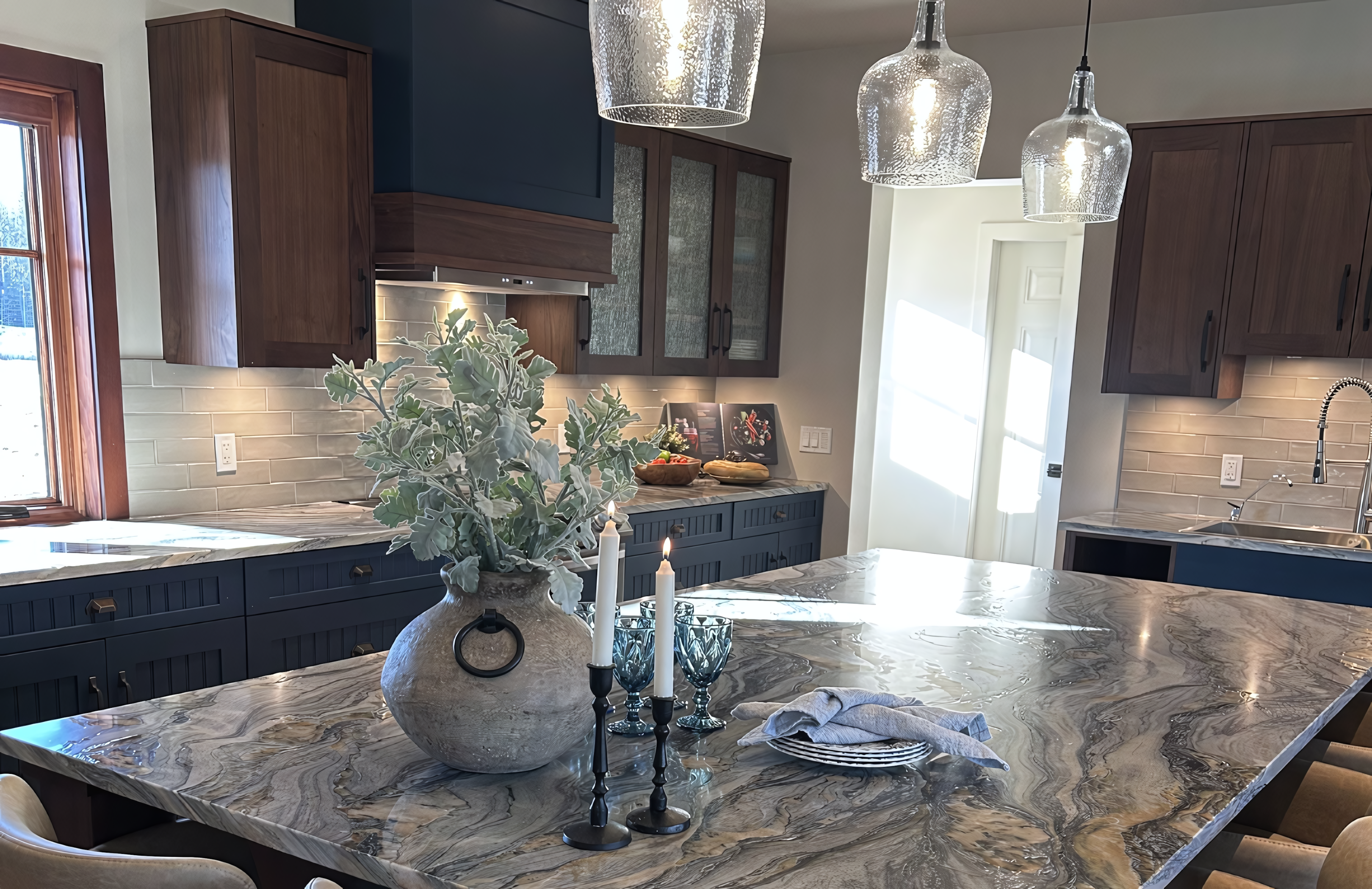 This expansive kitchen view captures the full integration of the tuxedo-style cabinetry into a modern open-concept living space. The design features a massive walnut-clad island with a dramatic quartzite waterfall countertop, providing a central anchor for seating and meal prep. To the right, floor-to-ceiling cabinetry in deep navy blue lacquer offers high-capacity storage, seamlessly flanking a stainless steel refrigerator. The workspace is highlighted by rich walnut upper units, reeded glass inserts, and a custom two-tone hood fan, all unified by a consistent architectural aesthetic that bridges the kitchen and living areas.