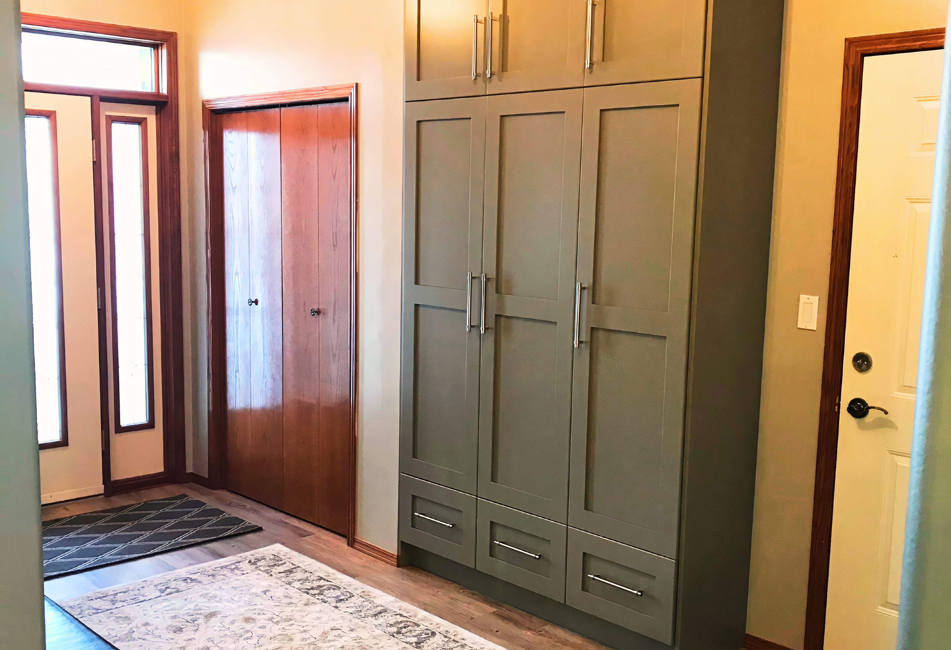 Tall built-in pantry/storage cabinet with a painted shaker-style door profile, long vertical pulls, and lower drawer storage