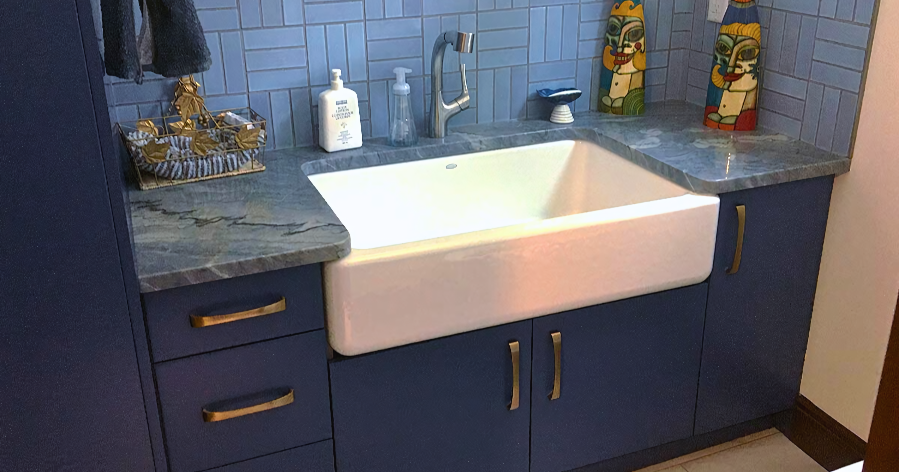 Modern bathroom vanity in deep navy blue with a matte finish, paired with a white farmhouse-style apron sink and brushed nickel faucet.
