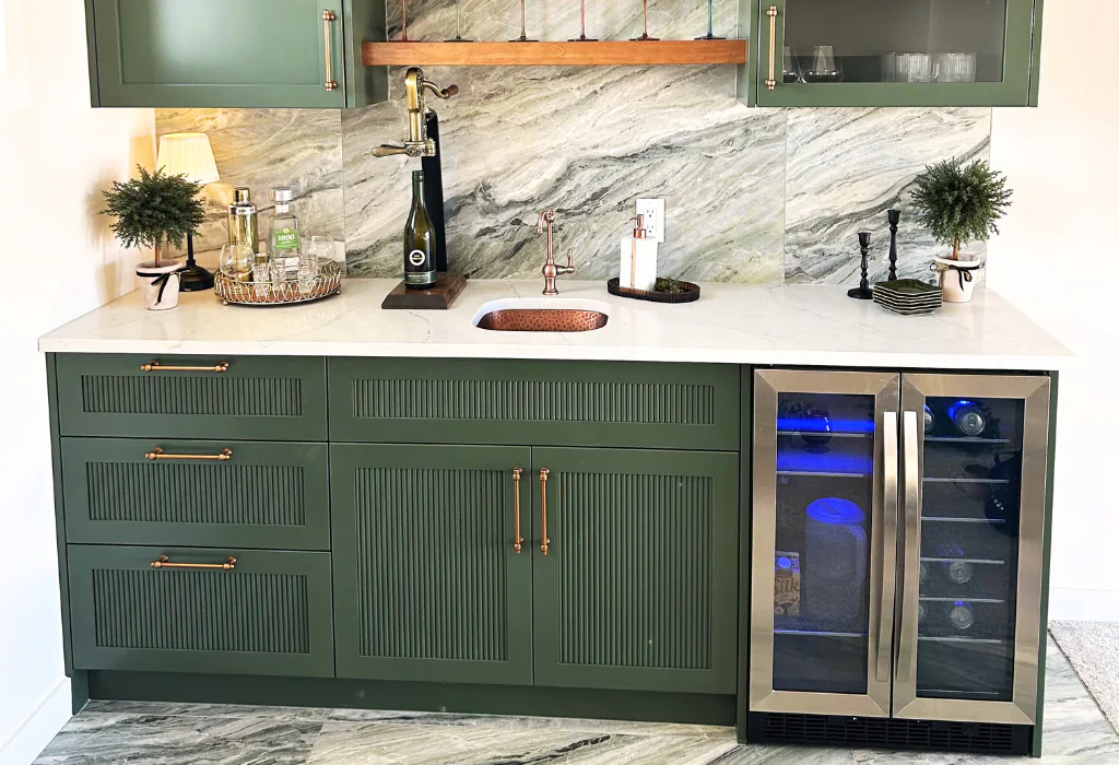 Custom sage green wet bar cabinetry featuring fluted tambour cabinet doors, micro-shaker profiles, and a flush-integrated dual-zone beverage refrigerator.